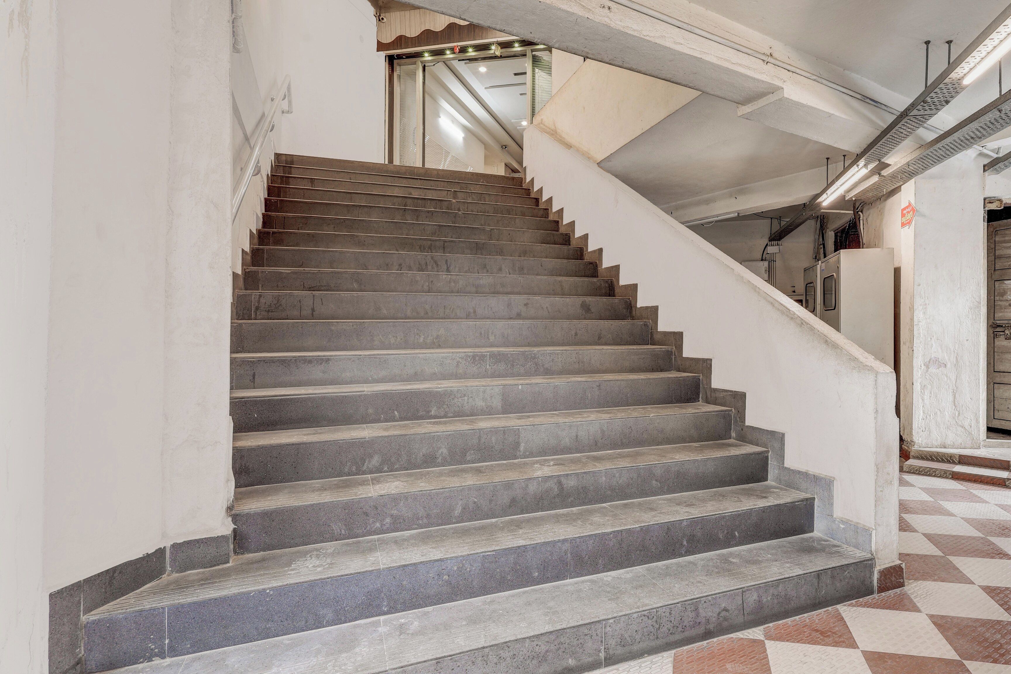 Una escalera con un piso de patrón a cuadros que conduce a una puerta con picaporte de metal.