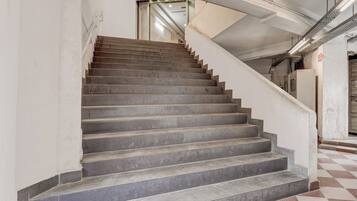 Una escalera con un piso de patrón a cuadros que conduce a una puerta con picaporte de metal.