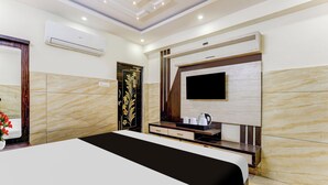 A hotel room with a bed, a TV mounted on the wall, a small table with a kettle, and a decorative door. - Super Hotel O Eluru Railway Station (Eluru)