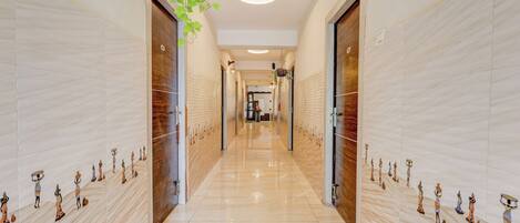 A hallway with a polished floor, flanked by walls with decorative panels and doors.