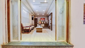 A hotel lobby with a reception desk, seating area, and a decorative wall. - Super Hotel O Eluru Railway Station (Eluru)