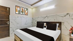 A modern bedroom with a large bed, marble walls, and a wooden door. - Super Hotel O Eluru Railway Station (Eluru)