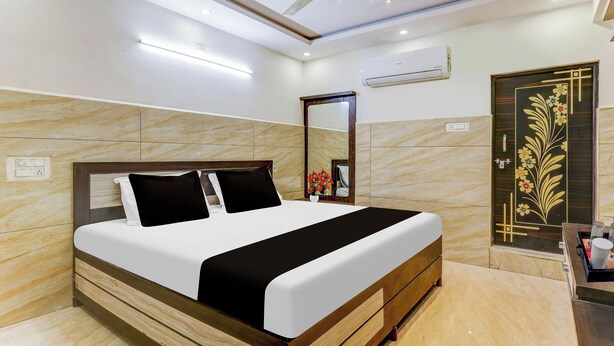 A hotel room with a bed, a ceiling fan, an air conditioning unit, a mirror, and a decorative door. - Super Hotel O Eluru Railway Station (Eluru)