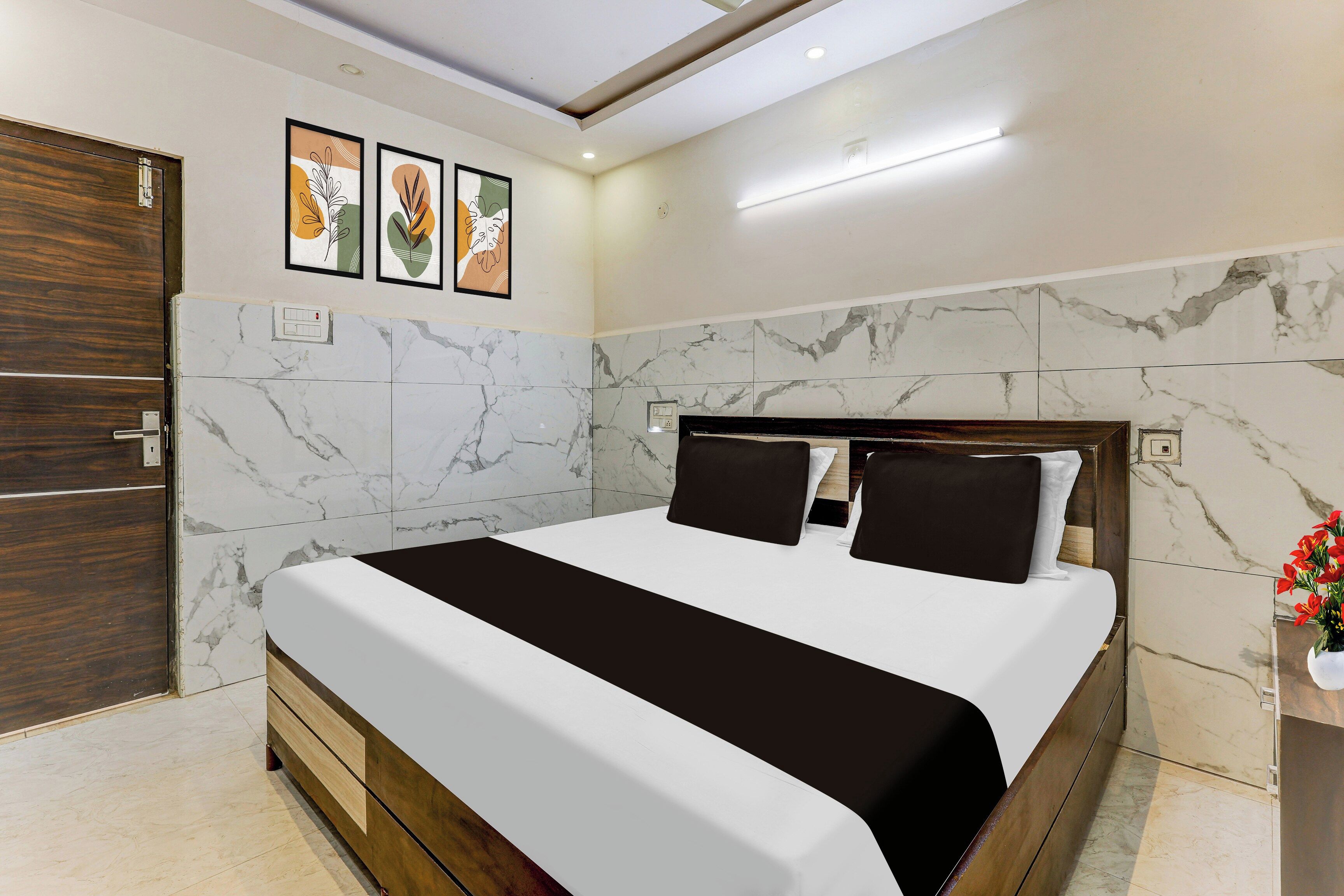 A modern bedroom with a large bed, marble walls, and a wooden door.