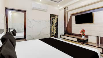 A modern hotel room with a large bed, a flat-screen TV mounted on the wall, and a wooden vanity with a mirror.