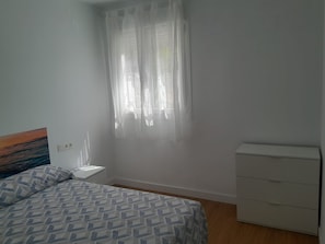 A bedroom with a bed, a nightstand, a dresser, and a window with sheer curtains. - Blue Summer B Apartment (Nerja)
