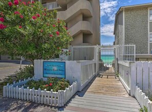 A gated entrance to a property with a sign indicating 'Mersmer Beach Villas' and a view of a building with a stone facade. - 🌊Miramar Beach Villa 112 | Beach Steps Away~Pool~Sleeps 16~Beach Service🏝️ (Miramar Beach)