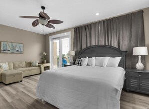 A bedroom with a bed, a ceiling fan, a nightstand with a lamp, a couch, and a painting on the wall. - 🌊Miramar Beach Villa 112 | Beach Steps Away~Pool~Sleeps 16~Beach Service🏝️ (Miramar Beach)