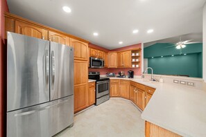 A modern kitchen with stainless steel appliances, wooden cabinets, and a teal accent wall. - Crane Cabin - Luxurious and spacious 3/2 house on Lake Sebring (Sebring)