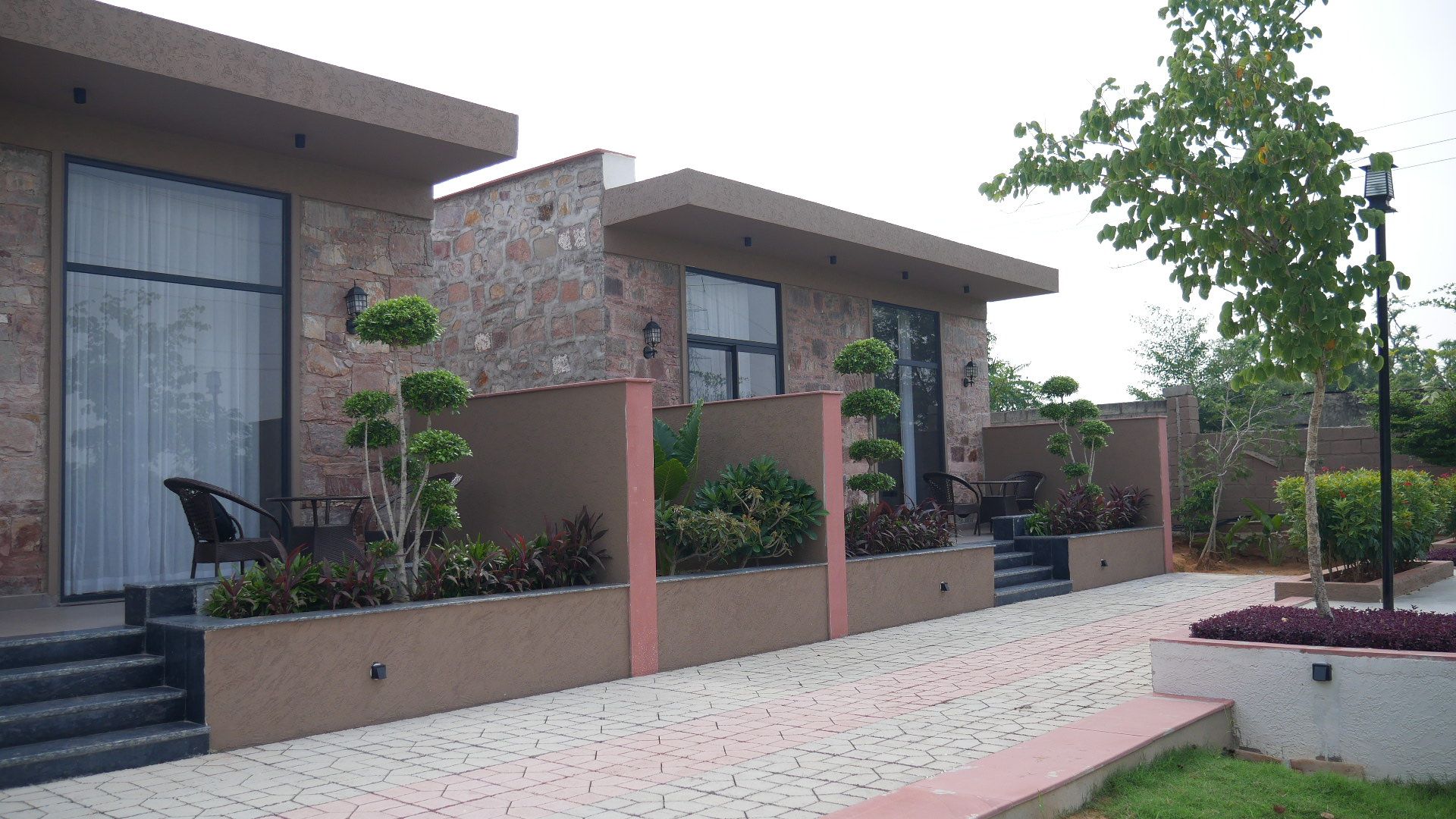 Un edificio moderno con fachada de piedra, amplios ventanales y un sendero pavimentado.