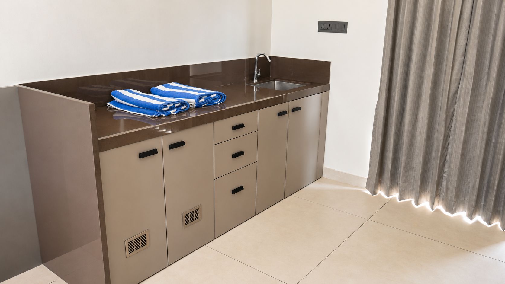 A modern kitchen with a stainless steel sink, a built-in oven, and a countertop with towels.