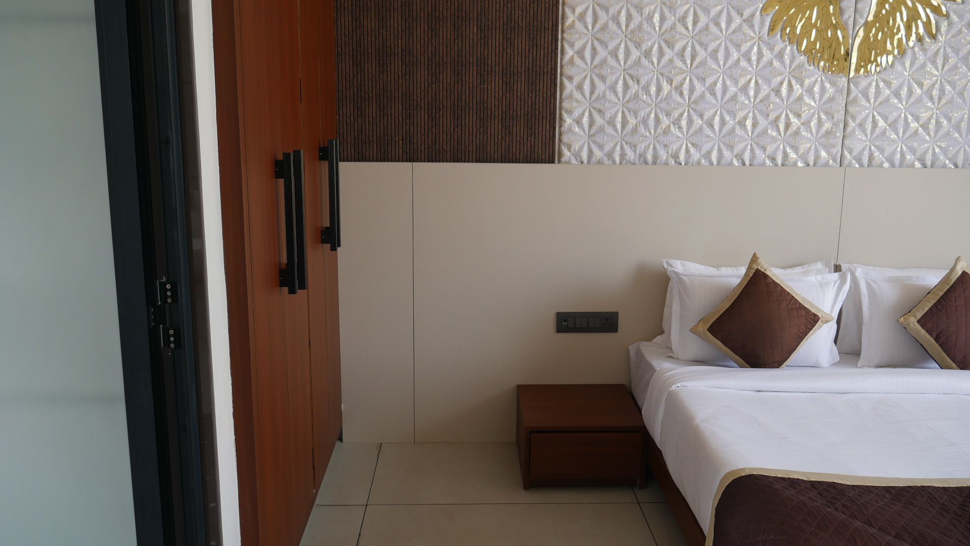 Quarto com cama, mesa de cabeceira e guarda-roupa.
