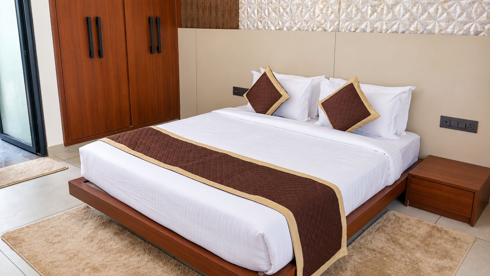 Ein modernes Hotelzimmer mit einem großen Bett, Holznachtischen und einer Schiebetür.