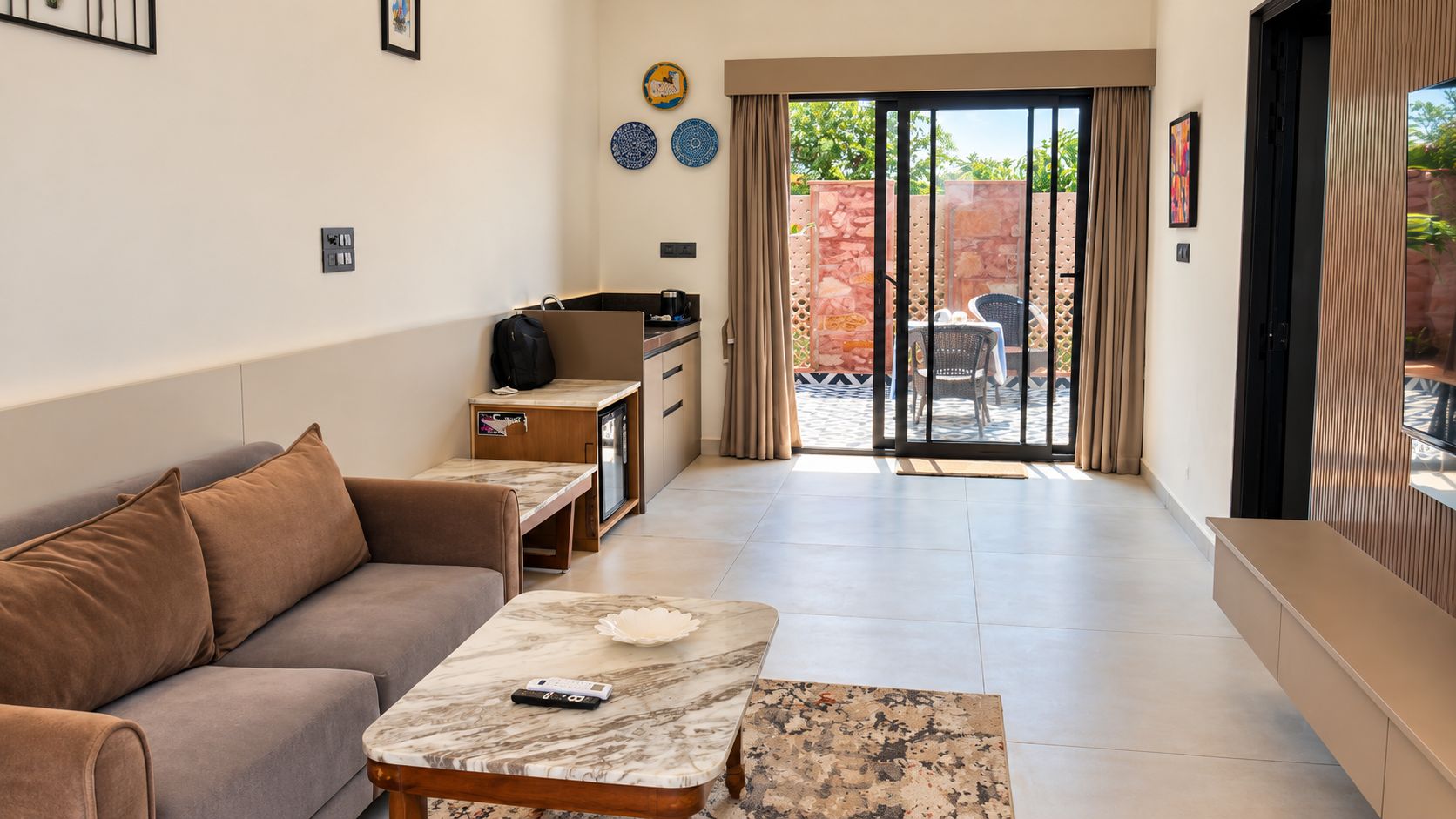 A living room with a sofa, a coffee table, a TV, and a sliding glass door leading to an outdoor area.