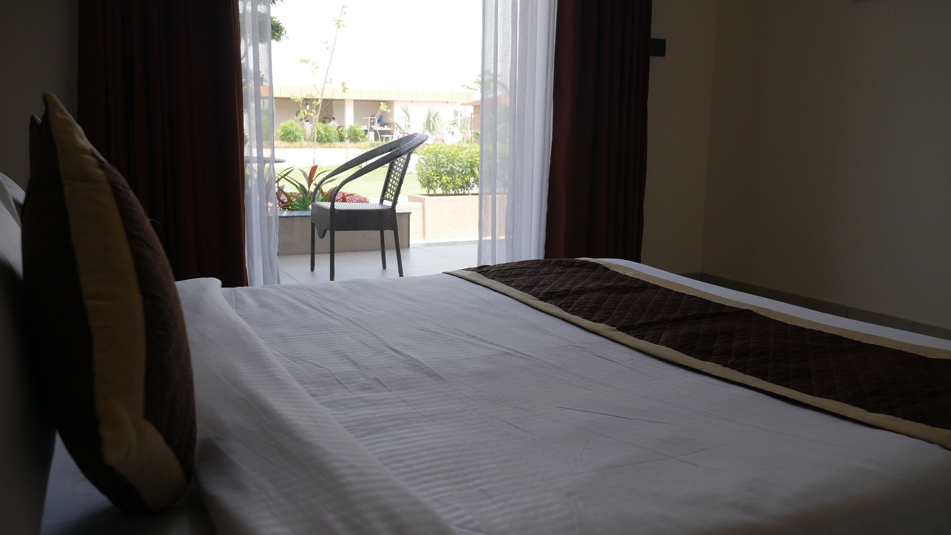 A hotel room with a bed, a chair, and a view of the outside.