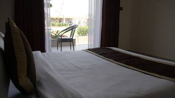 A hotel room with a bed, a chair, and a view of the outside.