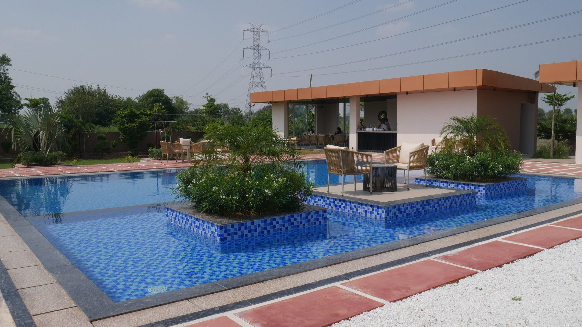 Piscina com bordas azulejadas, rodeada por um espaço de pátio com móveis de exterior.