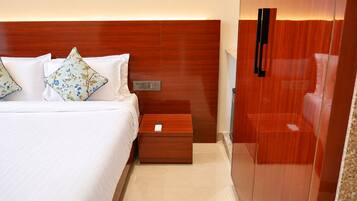 A hotel room with a bed, a nightstand, a wooden wardrobe, and a mirror.