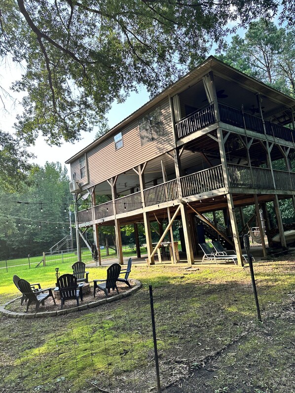 A wooden cabin with a balcony, outdoor seating area, and a view of the surrounding forest.