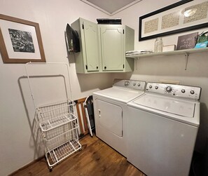 A laundry room with a washing machine, dryer, and a metal laundry basket.