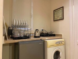 A compact kitchen with a dishwasher, a washing machine, a kettle, and a coffee maker. - Perfect 1-bedroom apartment with AC in welcoming Giza Governorate (Giza Governorate)