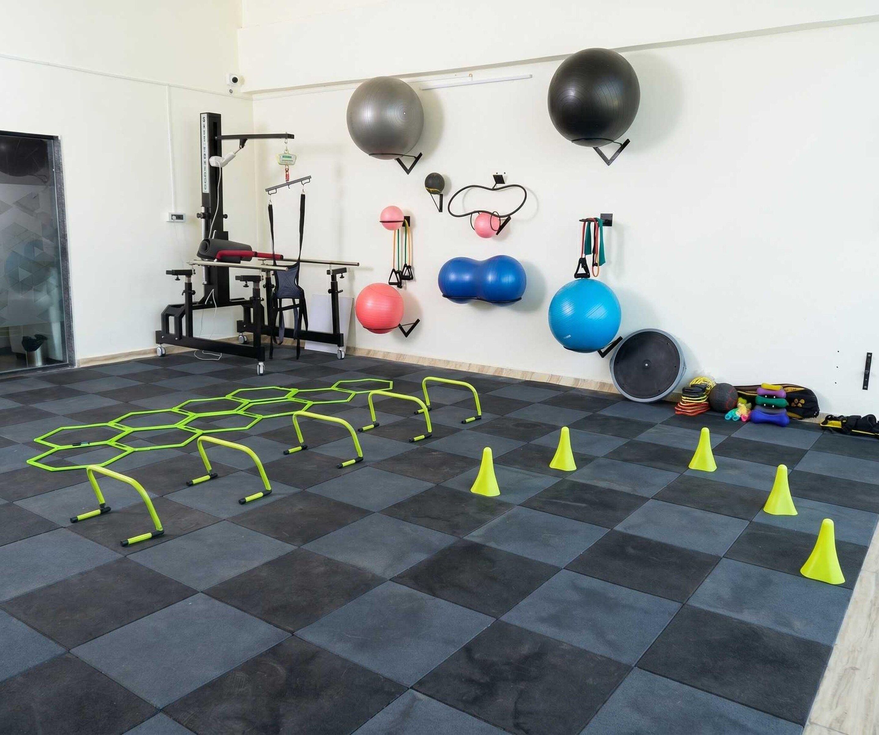 Una palestra con attrezzatura da allenamento, tra cui una panca per squat, palle mediche e fasce elastiche.