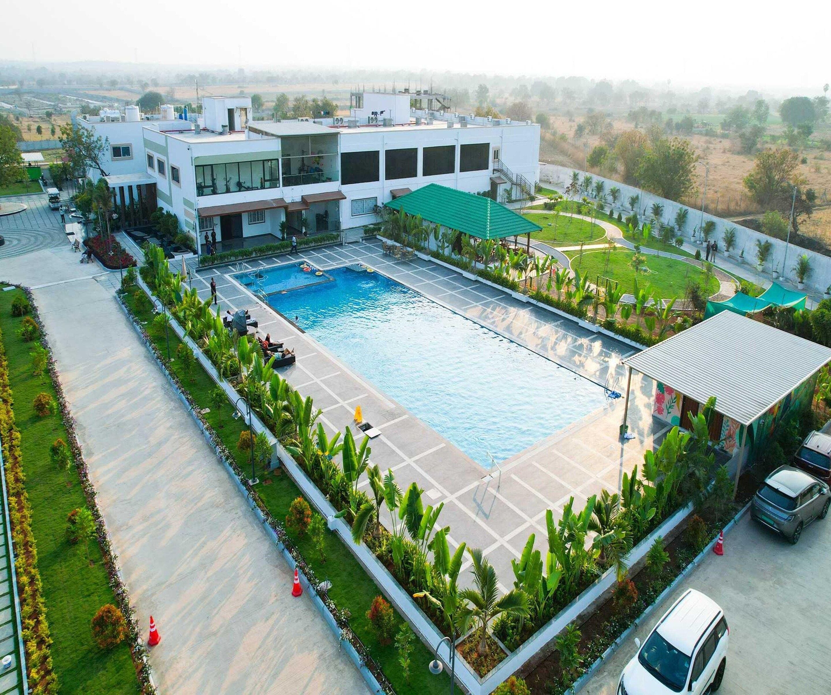 A large swimming pool surrounded by a landscaped area with a modern building in the background.