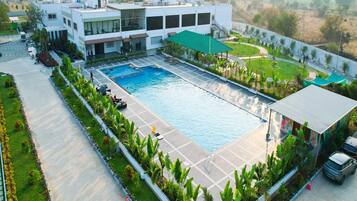 A large swimming pool surrounded by a landscaped area with a modern building in the background.