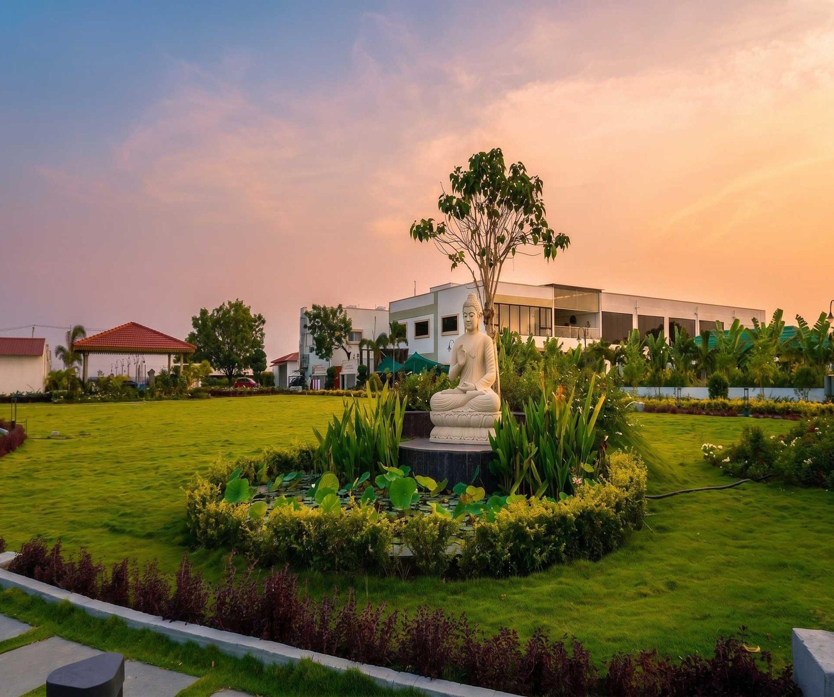 A statue in a landscaped garden with a modern building in the background.