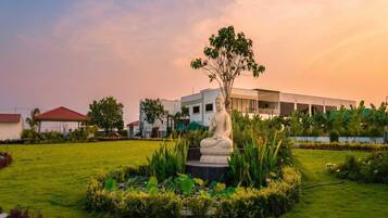 A statue in a landscaped garden with a modern building in the background.
