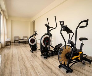 A gym with three stationary bikes, a bench, and a mirror. - Standard Twin Room Haritha Wellness Resort (Momanpet)