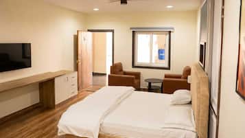 A hotel room with a bed, a desk, a chair, a television, and a window.