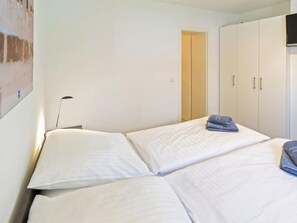 A bedroom with two beds, a wardrobe, and a door leading to another room. - Holiday Apartment With 1 Bedroom (Esens)