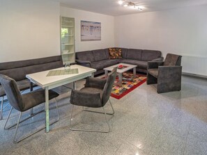 Ein modernes Wohnzimmer mit einer Eckcouch, einem kleinen Tisch und zwei Sesseln.