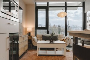 Un salon moderne avec un canapé, une table basse et une vue sur un paysage enneigé, visible à travers de grandes fenêtres.