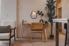 A room with a wooden desk, a chair, a potted plant, and a wall-mounted mirror.