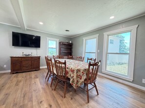 A dining room with a large table, chairs, a TV, and a wooden cabinet. - Fredericksburg Getaway with Private Pool (Fredericksburg)