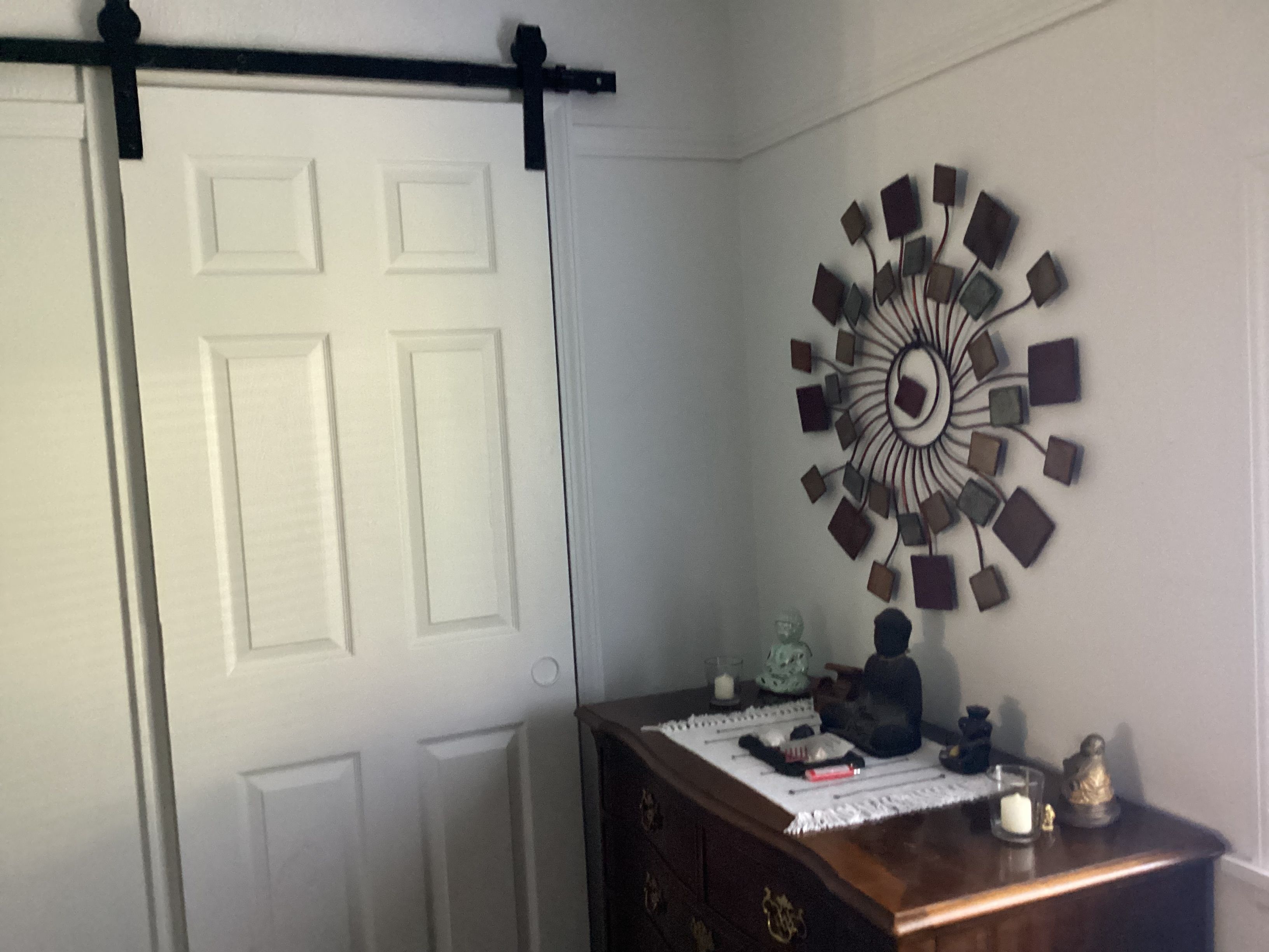 Une pièce avec une porte blanche, une commode en bois et une horloge décorative fixée au mur.