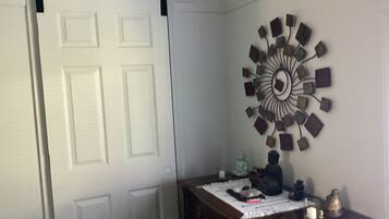 Une pièce avec une porte blanche, une commode en bois et une horloge décorative fixée au mur.