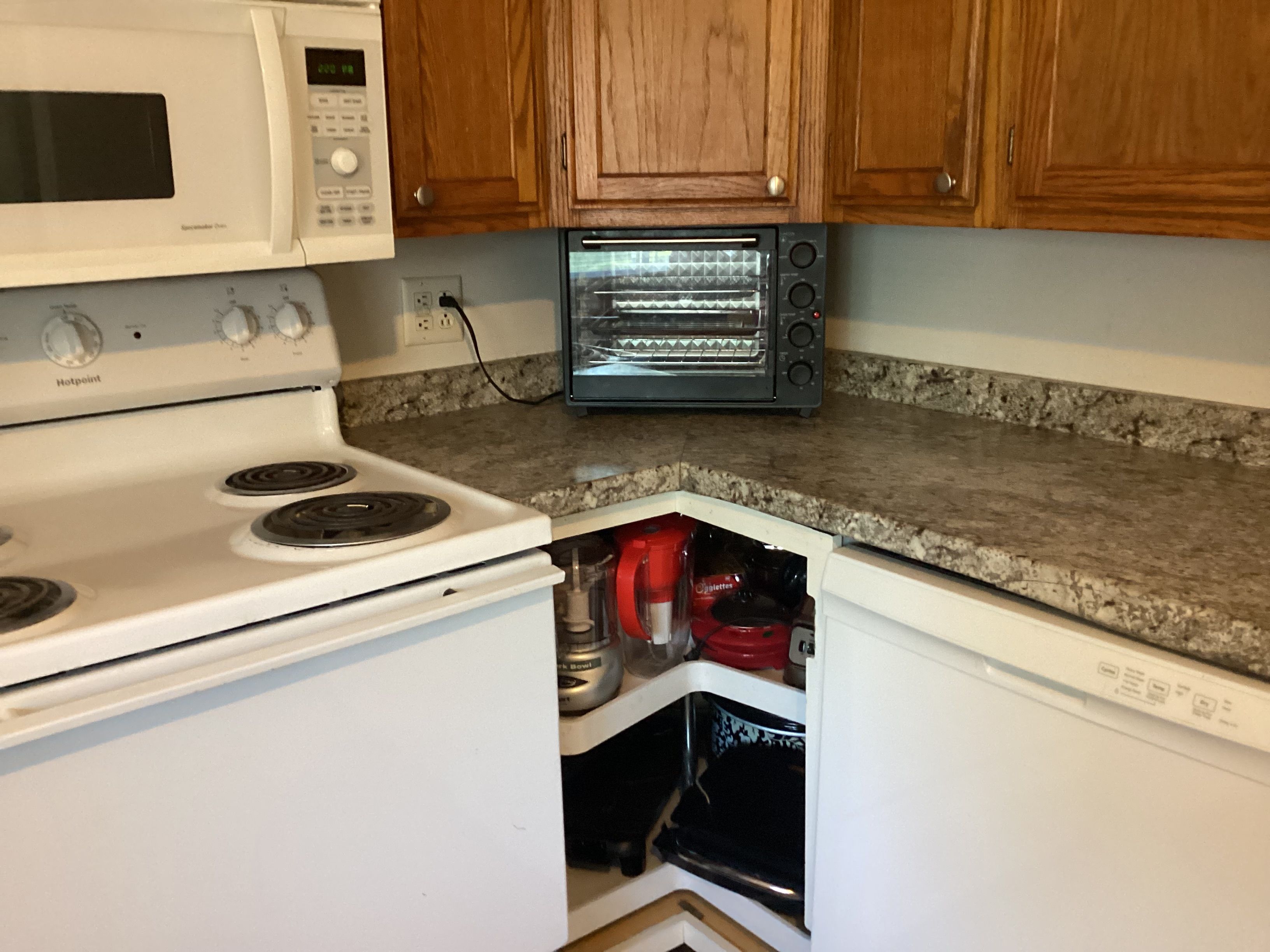 A kitchen with a white stove, a microwave, and a toaster oven.