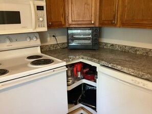 A kitchen with a white stove, a microwave, and a toaster oven.