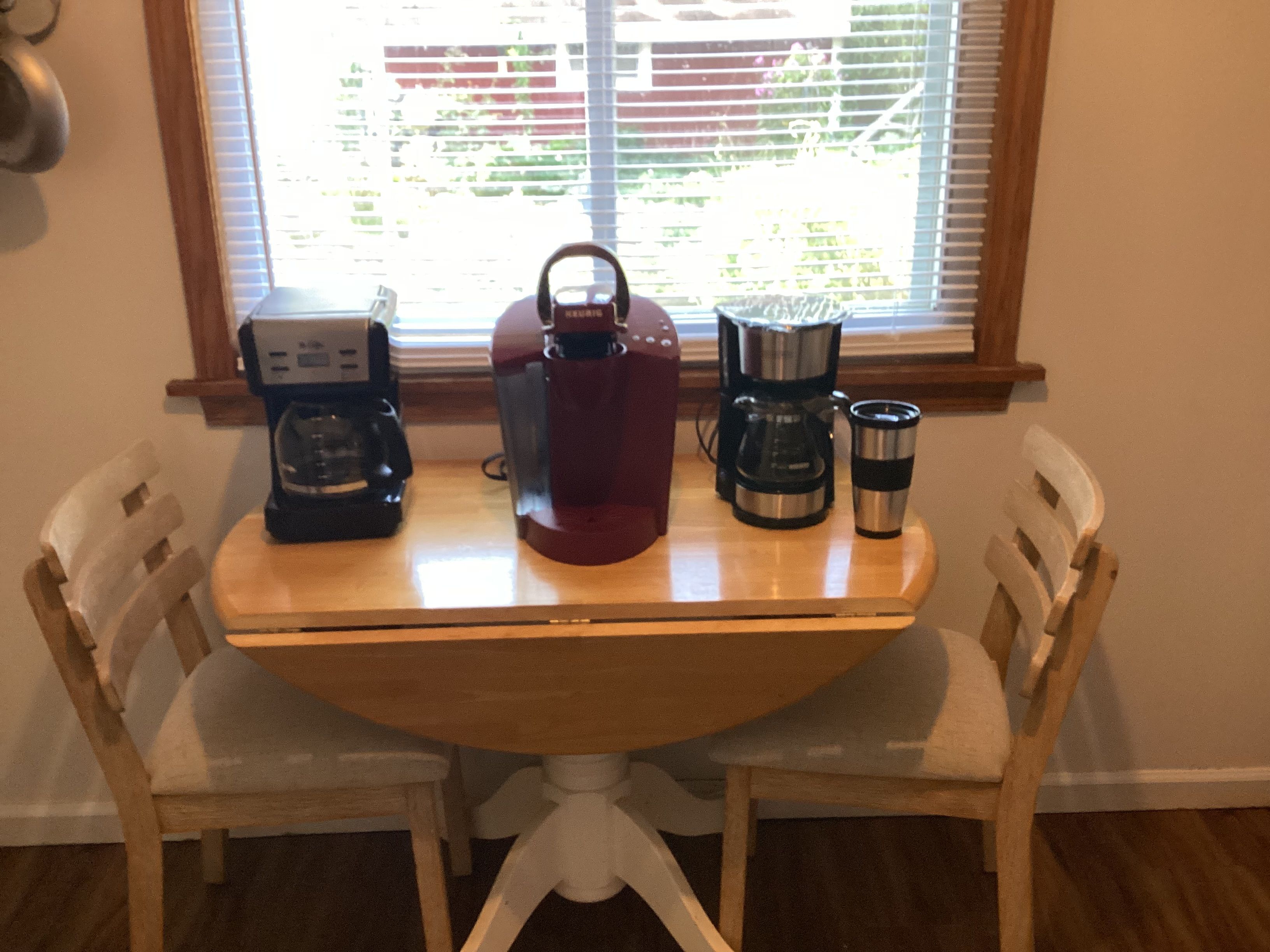 A dining table with a coffee maker, a kettle, and a mug.