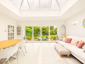 Um interior moderno com área de jantar, sofá e vista para um jardim através de portas de vidro.