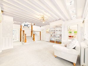 Ein geräumiger Wohnbereich mit Treppe, einem weißen Sofa und einem Bücherregal.