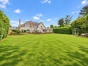 Ein großer, gepflegter Rasen mit einem Haus im Hintergrund.