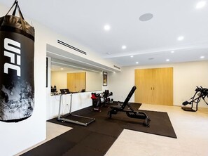 Uma academia com saco de pancadas, equipamentos de ginástica e um espelho grande.