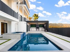 Ein moderner Wohnpool mit blauem Himmel und Bergen im Hintergrund.
