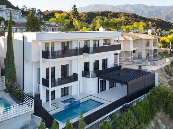 Ein modernes Mehrfamilienhaus mit Dachpool und Blick auf eine gebirgige Landschaft.
