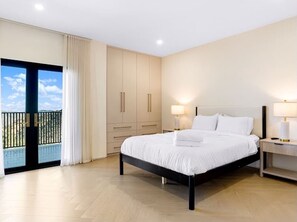 Ein Hotelzimmer mit Bett, Nachttischlampen, einem Kleiderschrank und einem Balkon mit Blick.