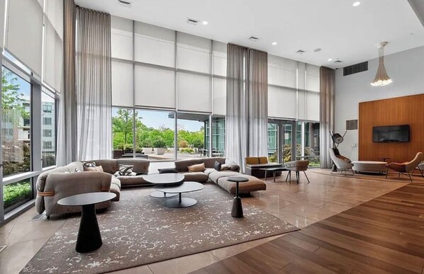 A modern living room with a sectional sofa, round coffee tables, and a flat-screen TV mounted on a wooden wall.